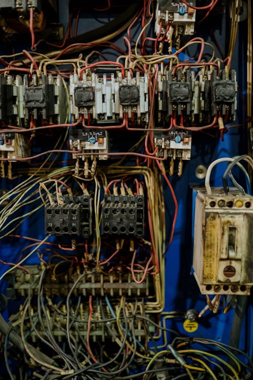 A worn and outdated electrical panel with tangled wires