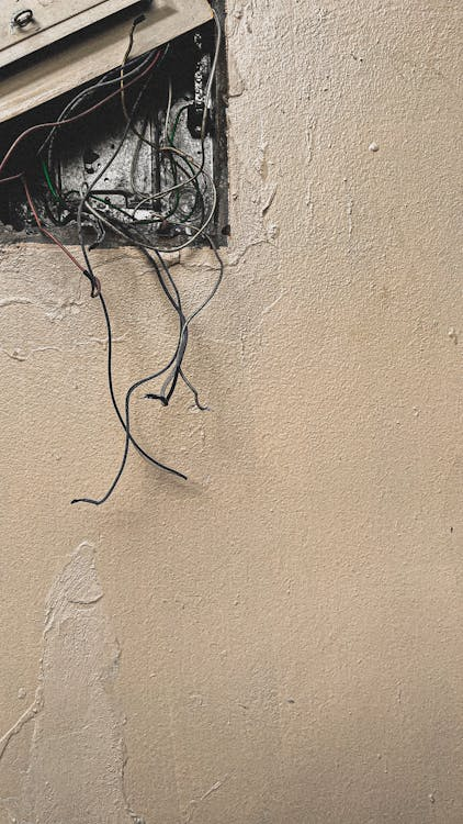 Frayed electrical wires exposed from inside the wall