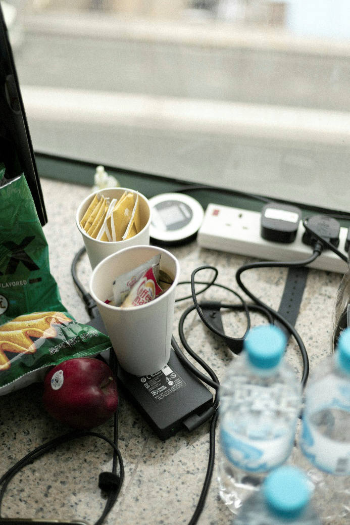 Overloaded power strip with tangled cords and plugged-in devices on a cluttered counter