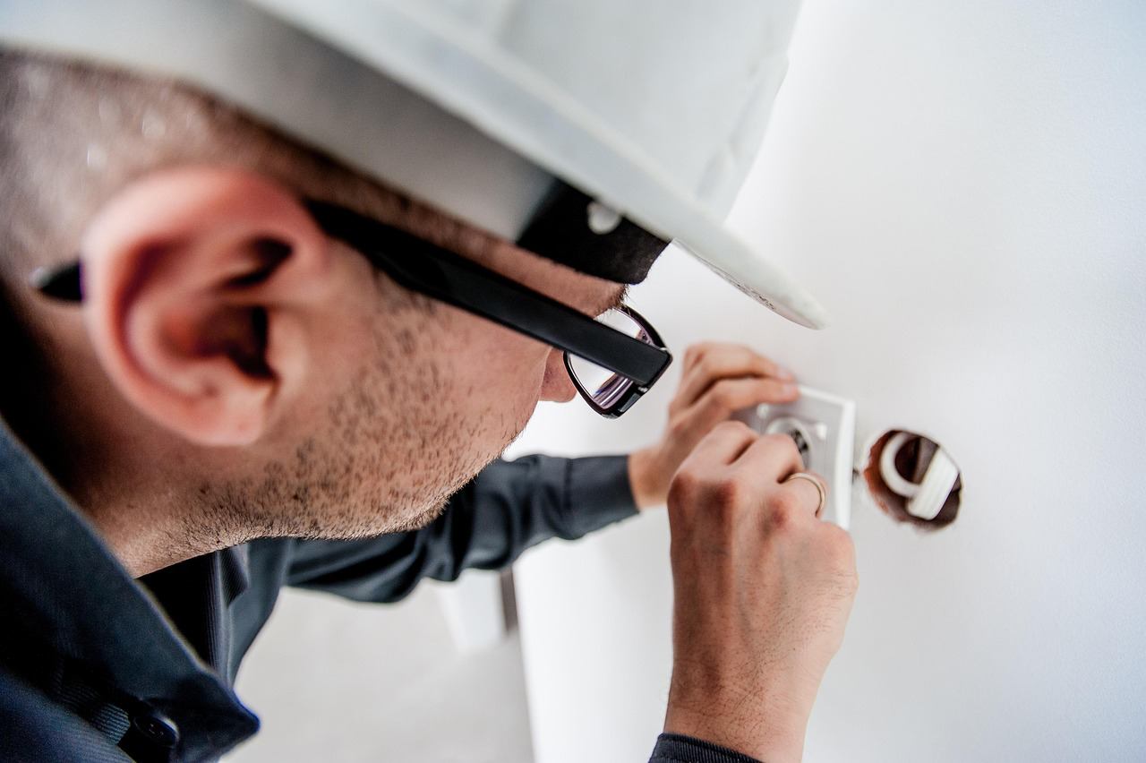 Professional electrician repairing a wall outlet with exposed wires