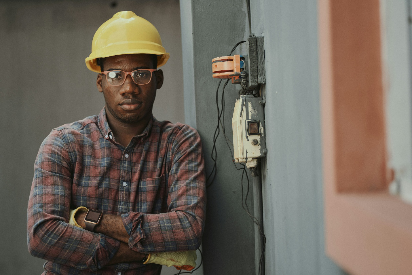 Licensed electrician standing beside exposed wiring outside a home