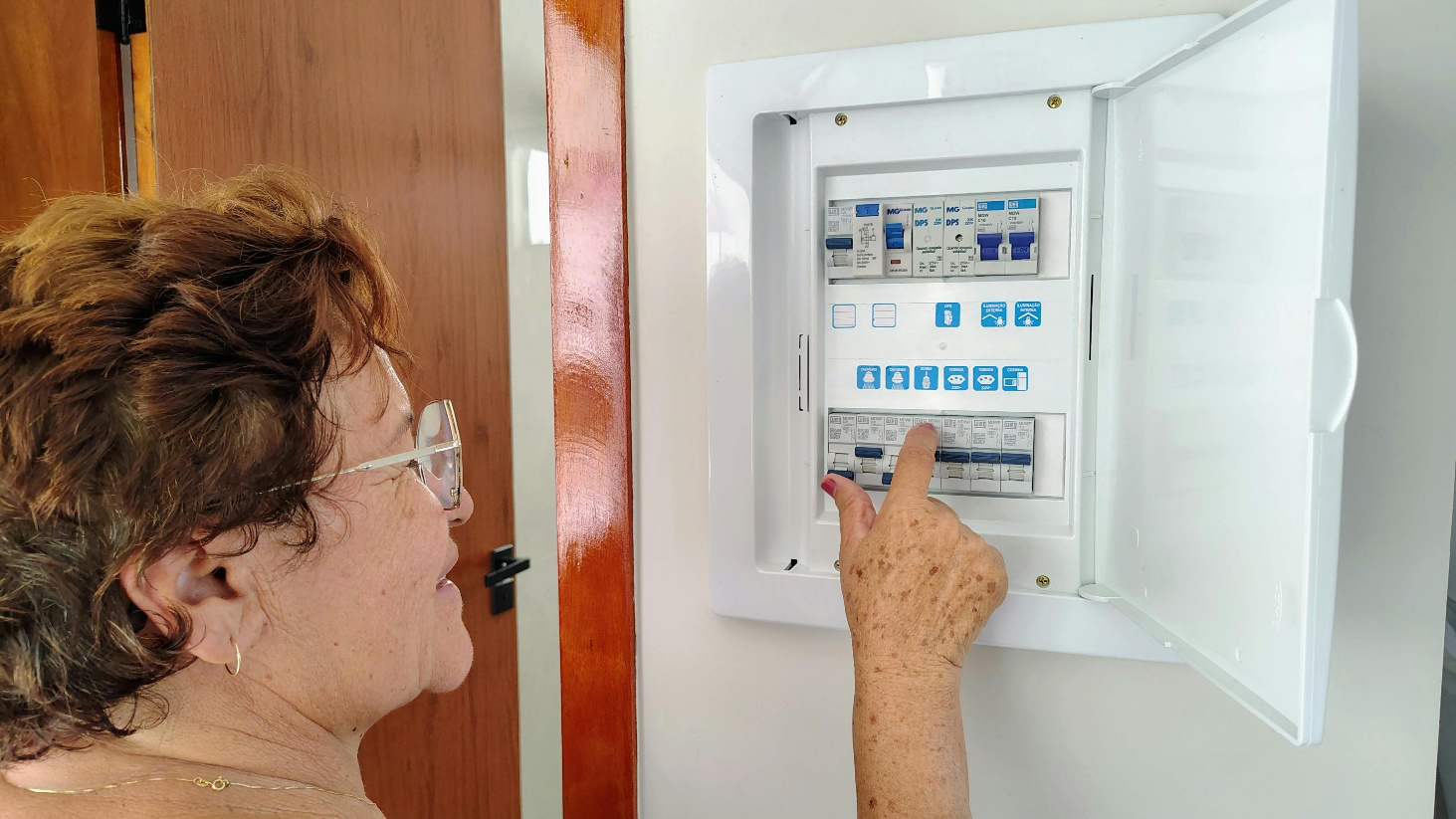 Senior woman inspecting a home circuit breaker panel